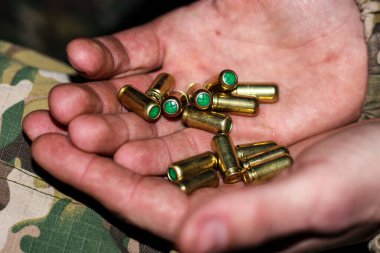 Savaştaki bir askerin kirli elleri, avuç içi boş 8 mm veya 9 mm 'lik mermi kovanları, yakın plan..