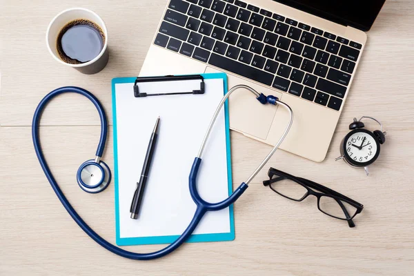 stock image Doctor desk with laptop, clipboard and stethoscope, online doctor consultation, top view