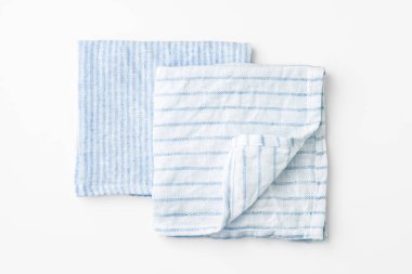 Katlanmış mavi keten peçeteler beyaz arkaplanda, üst görünümde.