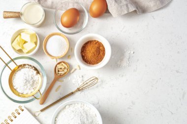Hamur işi veya kek malzemeleri, esmer şeker, tereyağı, un, yumurta ve süt mermer masa üzerinde çatal bıçak, fotokopi alanı ile üst görünüm