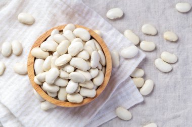 Ahşap kasede beyaz fasulye yığını keten masa örtüsü arka planda, fotokopi alanı olan üst manzara.