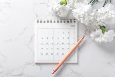 Kalem ve beyaz çiçekli takvim 2023 mermer zemin, üst görünüm
