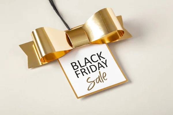 stock image Black friday sale tag with gold border and bow on beige background 