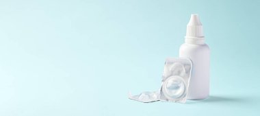 Açık mavi arkaplanda kontak lensler ve çözüm şişesi, boşluğu kopyala