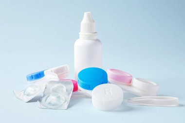 Kontakt lens solüsyonu şişesi ile kontakt lensler ve mavi arkaplan üzerindeki davalar