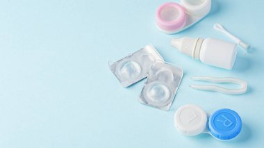 Konteynır, göz damlası ve cımbızla kontak lensleri mavi arkaplanda, boşluğu kopyala