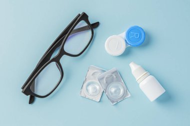 Mavi arka planda konteynırlı gözlük ve kontak lensler, üst görünüm