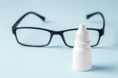 Mavi arka planda gözlüklü göz damlası.