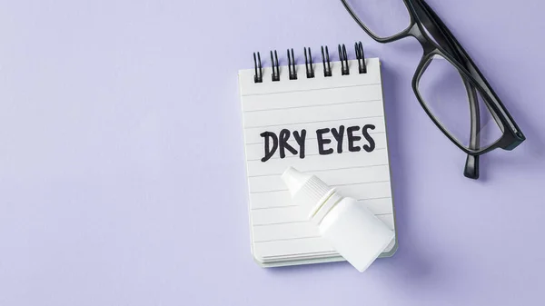 Dry eyes concept with eye drops with eyeglasses on pastel violet background, top view, copy space