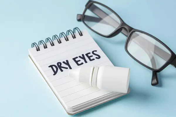 Dry eyes concept with eye drops and eyeglasses on blue background