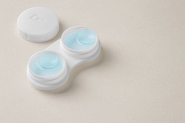 Bej arka planda sıvı çözeltisi olan beyaz kutuda kontak lensleri, boşluk kopyala