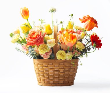 Hasır sepette çiçekler turuncu ve sarı güller, lale ve karanfil beyaz arka planda izole edilmiş.