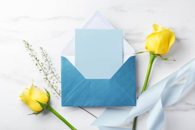 Mavi kartın içinde sarı güller ve beyaz masa zemininde kurdele var.