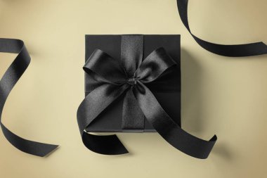 Altın arka planda kurdeleli siyah hediye kutusu, üst görünüm