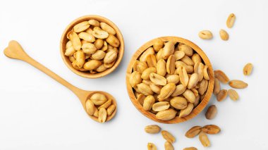 Beyaz arka planda izole edilmiş kaşıkla ahşap kasede fıstıklar, üst manzara.