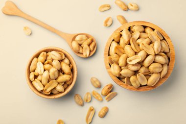 Ahşap kaselerde yer fıstığı, bej arka planda kaşık, üst manzara.