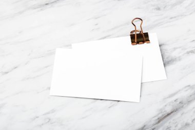 Bakır cilt klipsli kartvizit, beyaz mermer masa arka planında model.