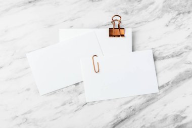 Beyaz mermer masa üzerinde bakır cilt klipsli kartvizit