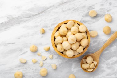 Macadamia fındıkları ahşap kasede kaşık ve çatlamış macadamia mermer mutfak tezgahında arka plan, üst manzara, kopyalama alanı