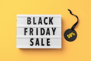 Kara Cuma indirimli sözcüğü ve sarı arka planda siyah kurdeleli indirimli etiket, üst görünüm