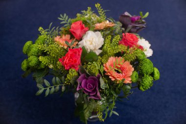 Çiçeksel bir buket kırmızı gerbera, karanfiller ve yeşil vazo, profesyonelce yapılmış