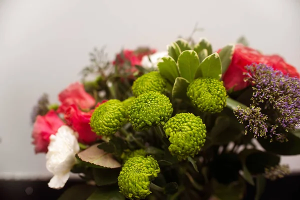 Gift flower arrangement close-up, a bouquet of mixed flowers of green chrysanthemums and carnations in a flower shop