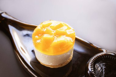 Koyu arkaplanda şarap şişesinden yapılmış bir tabakta mangolu turtalı sufle keki.