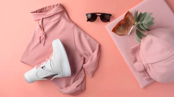 A pink shirt and white shoes are on a pink background, including sunglasses