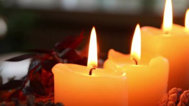 Noel çelengi üzerinde yanan dört mum, Noel arifesinde ve Noel tatillerinde, geleneksel Hıristiyan sembolü olarak süslenmiş bir Noel ağacının önünde romantik bir ruh haliyle parlıyor.