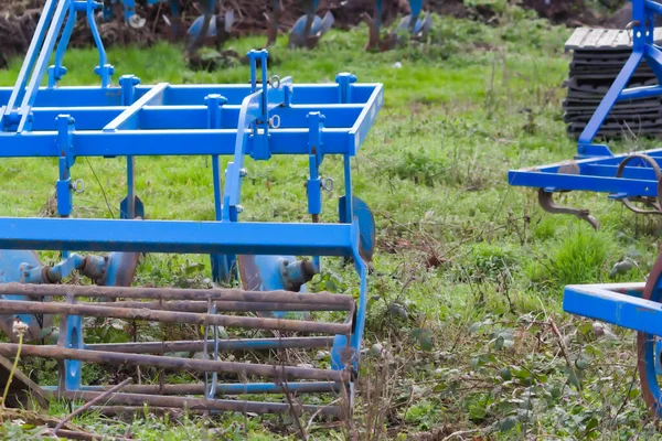 Blue heavy agricultural equipment like plow with sharp steel discs for agricultural field cultivation with tractor-drawn equipment for field work preparation facilitates hard farm work mechanization