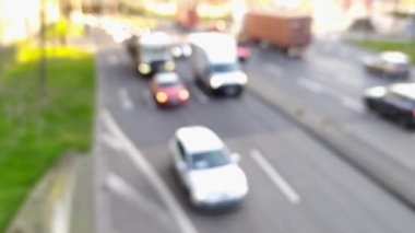 Bulanık şehir trafiği arka planında şehir trafiğinde hareket halindeki otomobiller şehir sokaklarında ve şehir taşımacılığı sektöründe kamyonlar ve otomobiller trafiğin yoğun olduğu saatlerde kasabalarda geziyor.