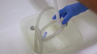 Mavi eldivenli bir adam solunum sistemi için Cpap hortumlarını ve Cpap maskesini temizler. Cpap makineli uyku apnesi hastalığı ve hijyenik temizlik için solunum maskesi.