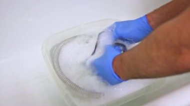 Mavi eldivenli bir adam solunum sistemi için Cpap hortumlarını ve Cpap maskesini temizler. Cpap makineli uyku apnesi hastalığı ve hijyenik temizlik için solunum maskesi.