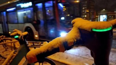Kar yağışı gecesinde escooter ya da hareketli bisiklet paylaşım kavramlarıyla karlı şehir sokaklarında karlı bir kış gecesi modern şehrin can güvenliğinde elektrikli araç olarak çevreye dost ulaşımı gösteriyor