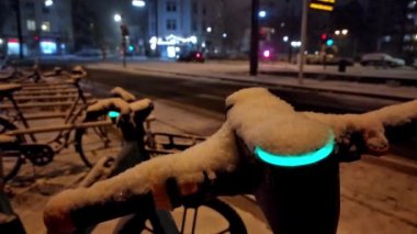 Kar yağışı gecesinde escooter ya da hareketli bisiklet paylaşım kavramlarıyla karlı şehir sokaklarında karlı bir kış gecesi modern şehrin can güvenliğinde elektrikli araç olarak çevreye dost ulaşımı gösteriyor