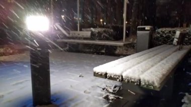 Soğuk kış gecelerinde kar yağışlı banklar tipi veya kar fırtınası sırasında şehirde yoğun kar yağışı, aydınlık ışık ve soğuk hava ile kaplı kar tanelerini gösterir.