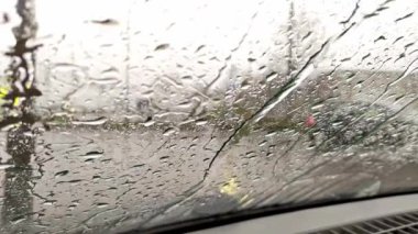 Şehir sokaklarının bulanık arka planına sahip araba camındaki yağmur damlaları kışın yağmurlu bir günde sağanak ve damlayan yağmur damlaları gök gürültülü fırtınalarda ve araba camlarında şiddetli yağış