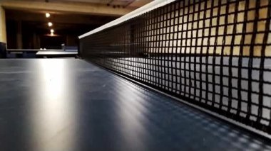 Yavaş hareket eden masa tenisi masası ve masa tenisi ağı net ağ detaylarıyla yakından izlenirken oyuncular boş zaman aktivitesi ve profesyonel spor yarışması etkinliği olarak masa tenisi ve ping pong oynuyorlar.