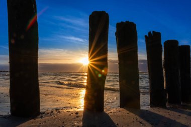 Parlayan güneş ve renkli gökyüzü ile güzel altın saat plaj günbatımı Kuzey Denizi kum tepeleri ve doğa gibi canlı renkler gösterir Okyanusta altın saat güneş ışığı seyahat yeri acenteleri olarak