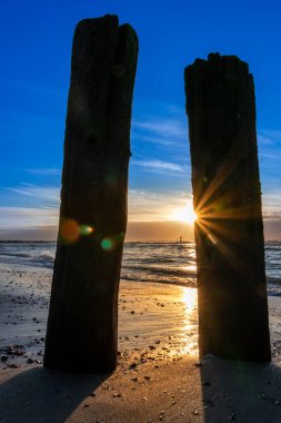 Parlayan güneş ve renkli gökyüzü ile güzel altın saat plaj günbatımı Kuzey Denizi kum tepeleri ve doğa gibi canlı renkler gösterir Okyanusta altın saat güneş ışığı seyahat yeri acenteleri olarak