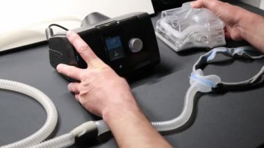 Cpap filtresi veya sağlık kontrolü için nemlendirici gibi terapi ekipmanlarını kontrol eden Cpap makineli erkek Avrupalı ve uyku apnesi maskeli yenilikçi sağlıklı uyku solunum sistemi için gece hazırlayıcı