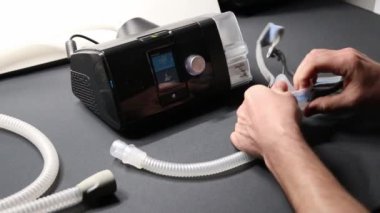 Cpap filtresi veya sağlık kontrolü için nemlendirici gibi terapi ekipmanlarını kontrol eden Cpap makineli erkek Avrupalı ve uyku apnesi maskeli yenilikçi sağlıklı uyku solunum sistemi için gece hazırlayıcı