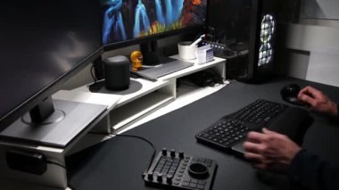 Avrupalı bir adam, ev ofisinden veya modern teknoloji kurulumu ve yayın için özel aygıtlara sahip serbest çalışan iki monitörde ergonomik işyeri ekipmanı kullanıyor ve uygulamaları kullanıyor