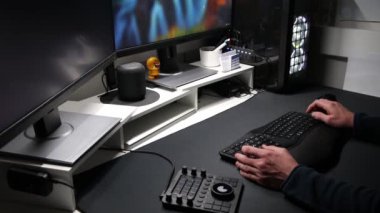 Avrupalı bir adam, ev ofisinden veya modern teknoloji kurulumu ve yayın için özel aygıtlara sahip serbest çalışan iki monitörde ergonomik işyeri ekipmanı kullanıyor ve uygulamaları kullanıyor