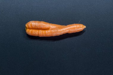 Siyah arka planda çarpık havuçlar. Organik çiftçiden birbirine aşık çiftlerin sembolü olarak. Bükülmüş havuç, idrarını tutamama ve vajinal mantar ya da evde yetişen sağlıklı beslenme.