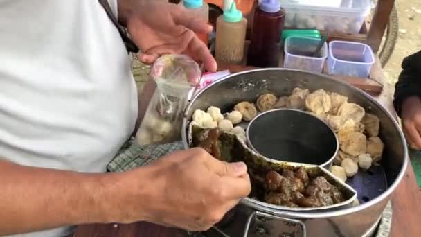 Penjual Bakso Sedang Menyiapkan Hidangan Untuk Pembeli Yang Masih Anak — Stok Video