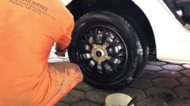Bir memur yıkandıktan sonra araba lastiğini parlatıyor..