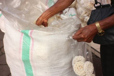 Geleneksel Kerupuk Satıcısı satılan krakerleri paketliyor.