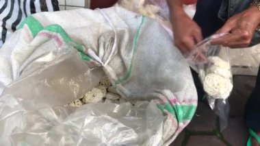 Bir adam müşterisinin kraker siparişini plastik bir torbaya koyuyor..
