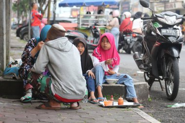 Küçük bir aile yol kenarında yemeğin tadını çıkarıyor.